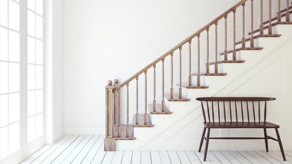 White room with staircase and wooden bench.